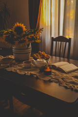 Candle lit amidst a cozy setup with tea, sunflowers, and apricots, exuding warmth and tranquility