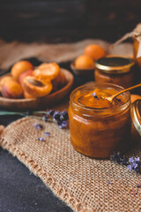 Homemade apricot jam with lavender flowers, surrounded by fresh apricots and lavender sprigs on a rustic burlap cloth