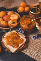 Homemade apricot jam with lavender flowers, surrounded by fresh apricots and lavender sprigs on a rustic burlap cloth