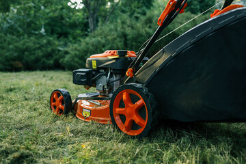 Bright orange lawn mower on a freshly cut lawn in a garden. The machine stands out against the greenery, showcasing its modern design and functionality for outdoor lawn maintenance