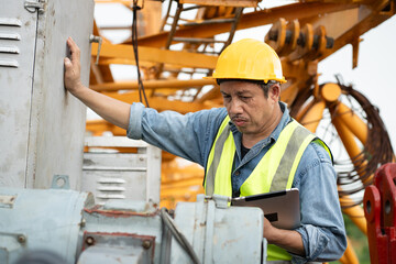 Asia engineer man worker checking machine and use tablet computer with spare crane background	