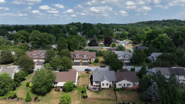 Tree-lined suburban neighborhood with neatly arranged houses in Pennsylvania. Residential streets and green lawns. Aerial truck shot in summer.