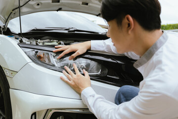 A male mechanic inspects a broken-down car on the roadside, while a female insurance agent provides assistance. The Caucasian driver, holding a clipboard, discusses the damage and files a claim for re