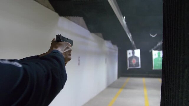 Shooting range practice. Slow motion of police man practicing with a handgun Glock shooting at indoor targets.