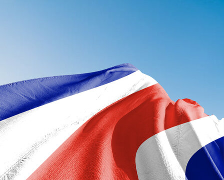 Costa Rica national flag cloth fabric waving on beautiful sky blue Background.