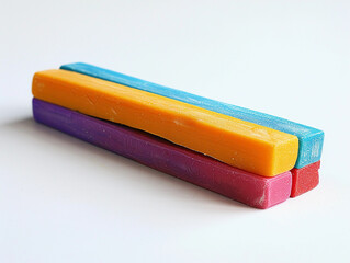 Colorful chalk sticks stacked on a white surface during daylight