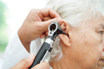 Otolaryngologist or ENT physician doctor examining senior patient ear with otoscope, hearing loss...