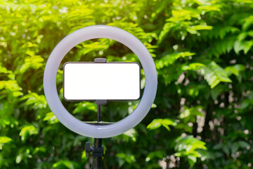 Horizontal smartphone with led ring lamp over on real nature background with copy space.