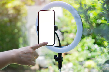 Woman's hand reach for the phone with blank screen, fixed on a round lamp