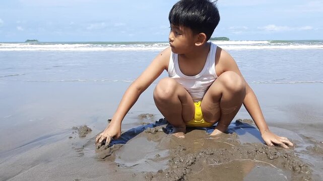 a boy playing in the dirt on the beach