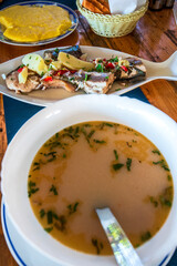 Bors de Peste, or Romanian Fish Soup, is a traditional dish served hot, garnished by a slice of crusty polenta (mamaliga).