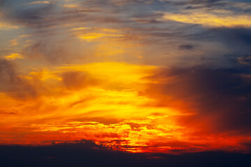 Beautiful sunset with a warm orange and yellow sky. The clouds are scattered throughout the sky, creating a sense of depth and movement. The colors of the sky are vibrant and calming
