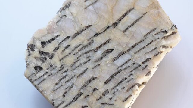 A sample of written granite. The granite-pegmatite mineral rotates in 3d on a white background. Polished cut