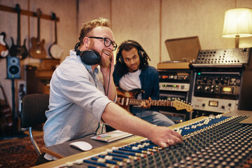 Producer and musican working on songs together in a studio