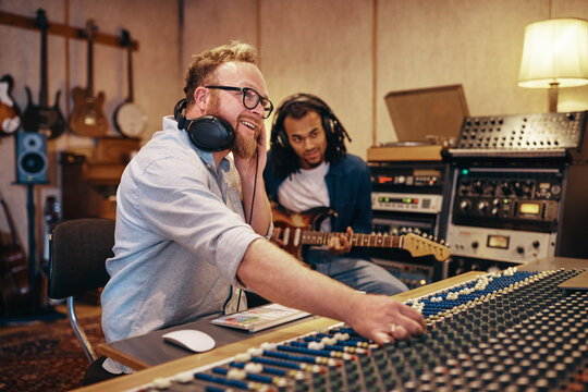 Producer and musican working on songs together in a studio