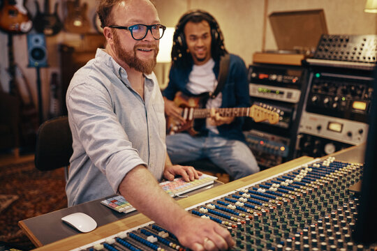 Producer and guitarist working on tracks in a music studio