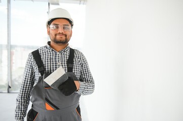 Indian Worker spreading plaster to wall with trowel, repairing works