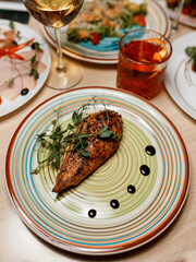 delicious juicy chicken with fresh herbs on a beautiful plate on a white tablecloth in a cozy nice restaurant