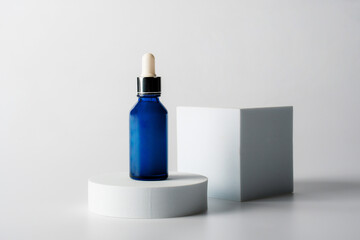 Blue glass cosmetic bottle, Skin care or sunscreen cosmetic with stylish props on white background.