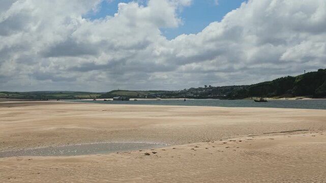 Right to left pan of view from Daymer Bay towards Padstow at low tide, sand in foreground