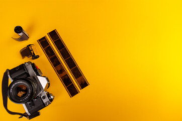 A vintage camera with 35mm film rolls in the bottom left corner, set against a yellow background. A...