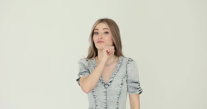 Woman shows throat slashing gesture with anger on gray background. Lady with long loose hair signals dire threat towards person provoking during conflict