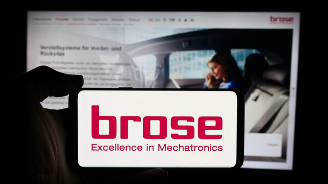 Stuttgart, Germany - 08-01-2024: Person holding cellphone with logo of German automotive company Brose Fahrzeugteile SE Co. KG in front of webpage. Focus on phone display.