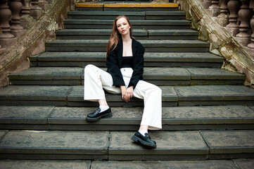 Young woman with long hair black jacket and white trousers street style