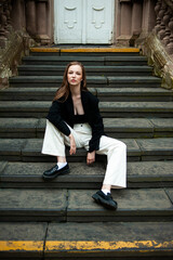 Young woman with long hair black jacket and white trousers street style