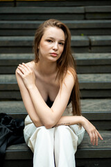 Young woman with long hair black jacket and white trousers street style