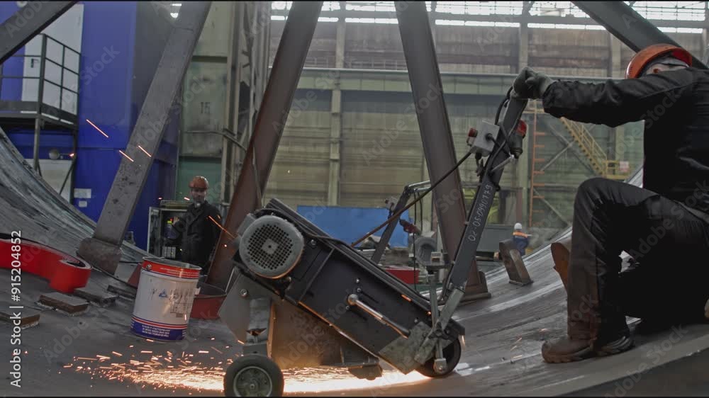 Poster worker with grinding machine on industrial structure. stock clip. worker with belt grinding machine 