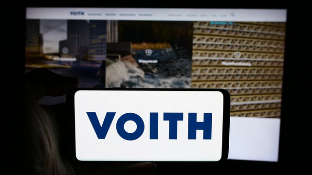 Stuttgart, Germany - 08-02-2024: Person holding cellphone with logo of German technology company Voith GmbH Co. KGaA in front of business webpage. Focus on phone display.