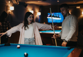 Group of friends gathered around a pool table, enjoying a game in a dimly lit billiards room.