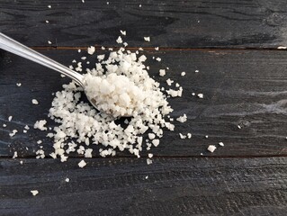 Food ingredient coarse table salt in spoon on the wooden table 