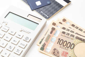 白背景に電卓と預金通帳と一万円