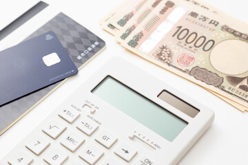 白背景に電卓と預金通帳と一万円