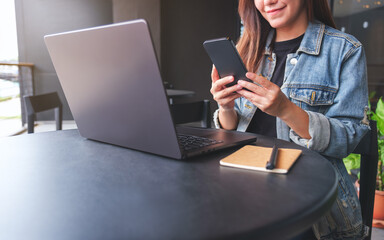 Closeup image of a young woman using smart phone and laptop computer