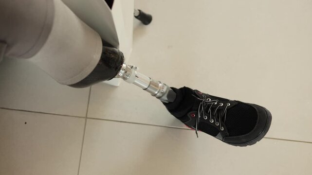 A person with a prosthetic leg sits and adjusts their prosthetic leg.