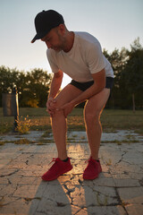 Man with injured and painful knee during jogging and exercise in a park.