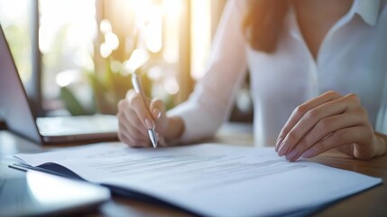 a woman signing a document on a laptop