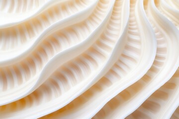 Close-up image of a seashell's layered, wavy texture in soft beige and cream tones