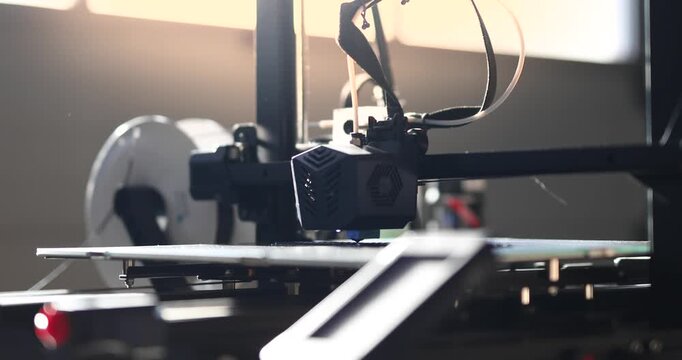 Close-up of a 3D printer head working in the rays of the setting sun. 3D printing technology in dynamic lighting, perfect for illustrating modern manufacturing.
