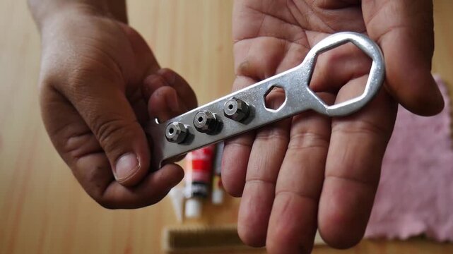Hand holding 3 pieces of rivet gun interchangeable head nozzle attached to the spanner
