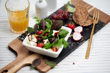 Fresh ruccola, red basil salad with balsamic vinegar and a glass of orange juice