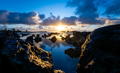 Panoramic view of north coast near Anse la Raie on Mauritius island with idyllic sunset atmophere and colorful sky. Silhouettes of volcanic black rocks at low tide. Paradisiacal  vacation destination.