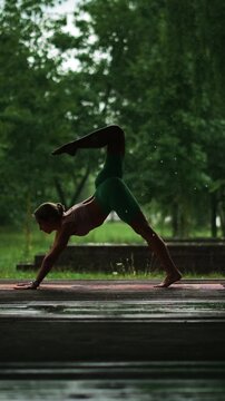 Girl doing yoga in the rain with trees in the background