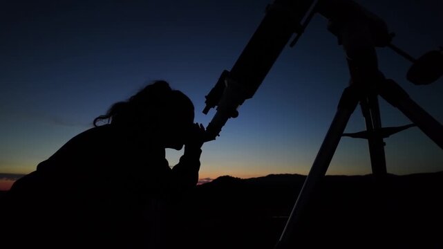 Amateur astronomer looking at the evening skies, observing planets, stars, Moon and other celestial objects with a telescope.	
