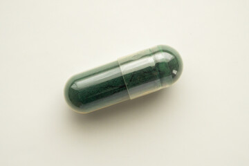 Green herbal medicine capsule on white background