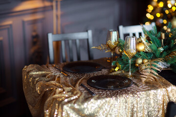 Festively served table. Decor in the style of winter Christmas holidays. Valentine's day romantic dinner. Glasses with imitation of a drink and blurred lights on the background.
