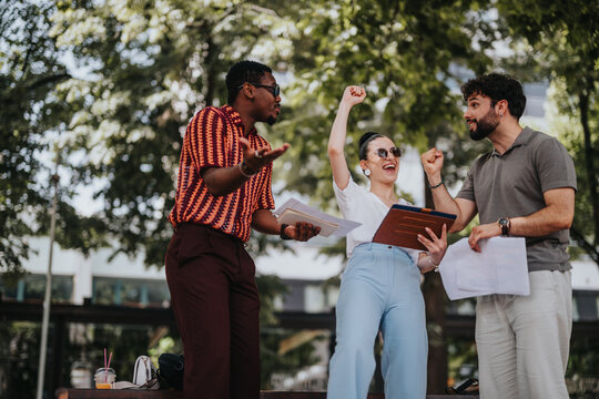 Diverse group of colleagues celebrating a successful project outdoors. Casual setting with energetic expressions, teamwork, and joy.